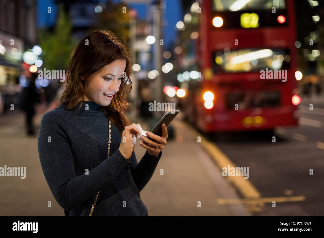 UK, London, woman checking her smartphone by the roadside Stock Photo