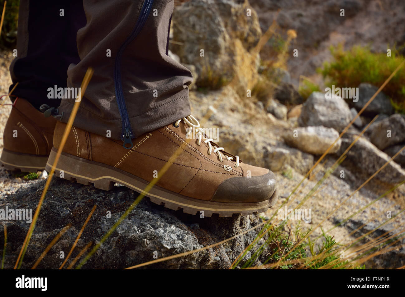 Outdoor hiking shoes in terrain. Men's legs feet in mountains. Hiker on Mountain trail path. Stock Photo