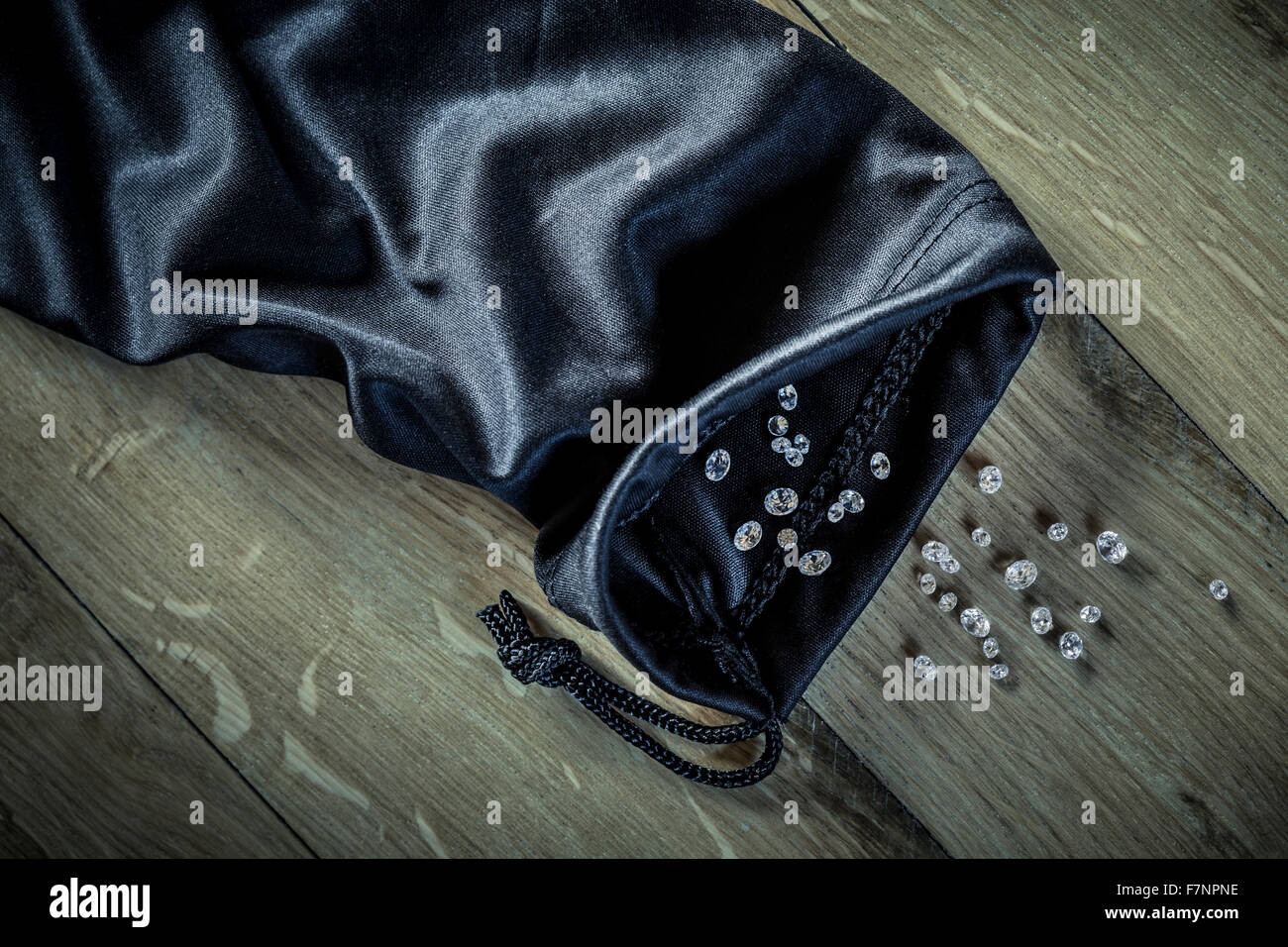 Diamonds spilling from a black cloth bag. Stock Photo