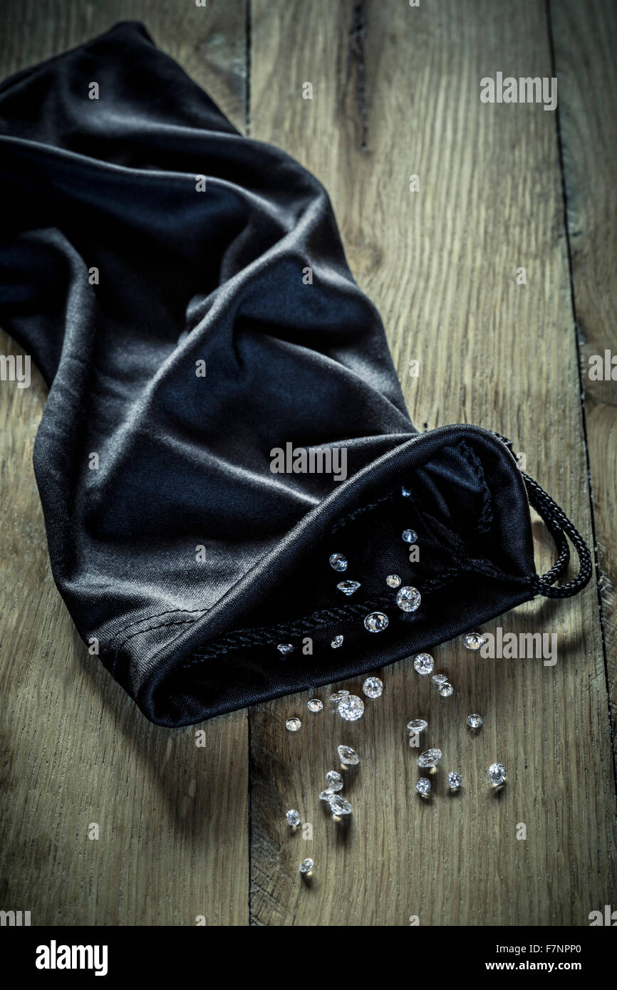 Diamonds spilling from a black cloth bag. Stock Photo