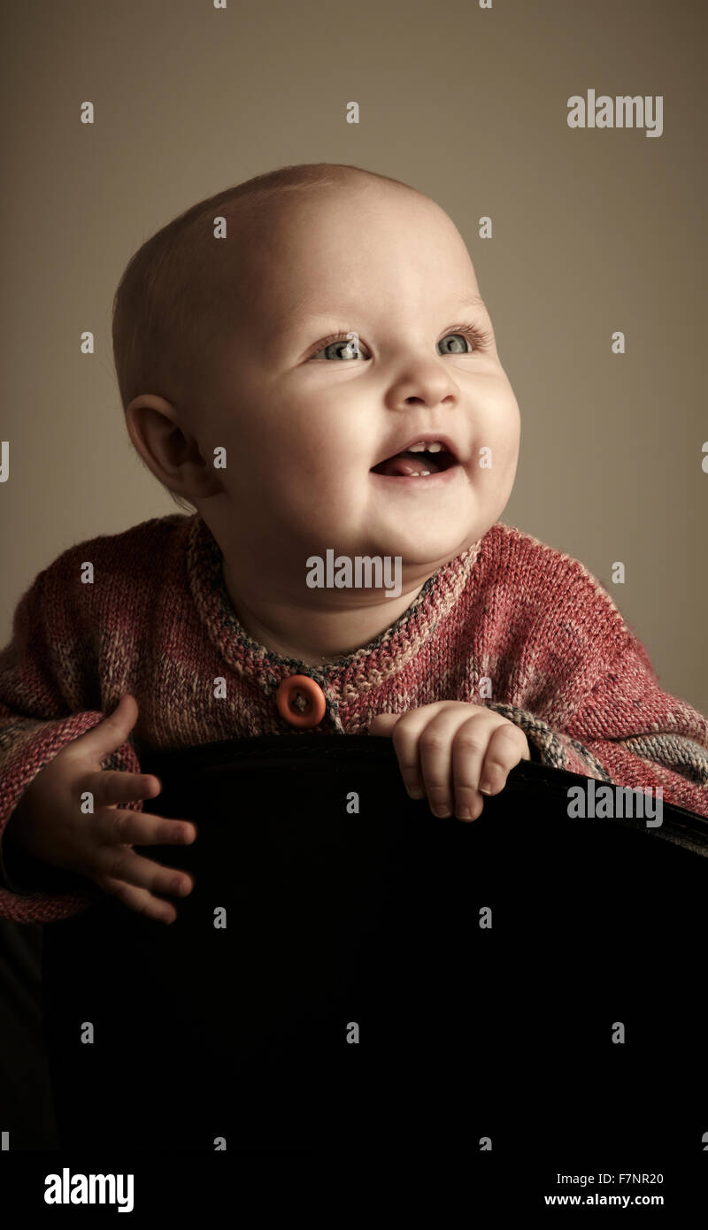 baby girl (8 month) looking cheerful and with expectation towards the light Stock Photo