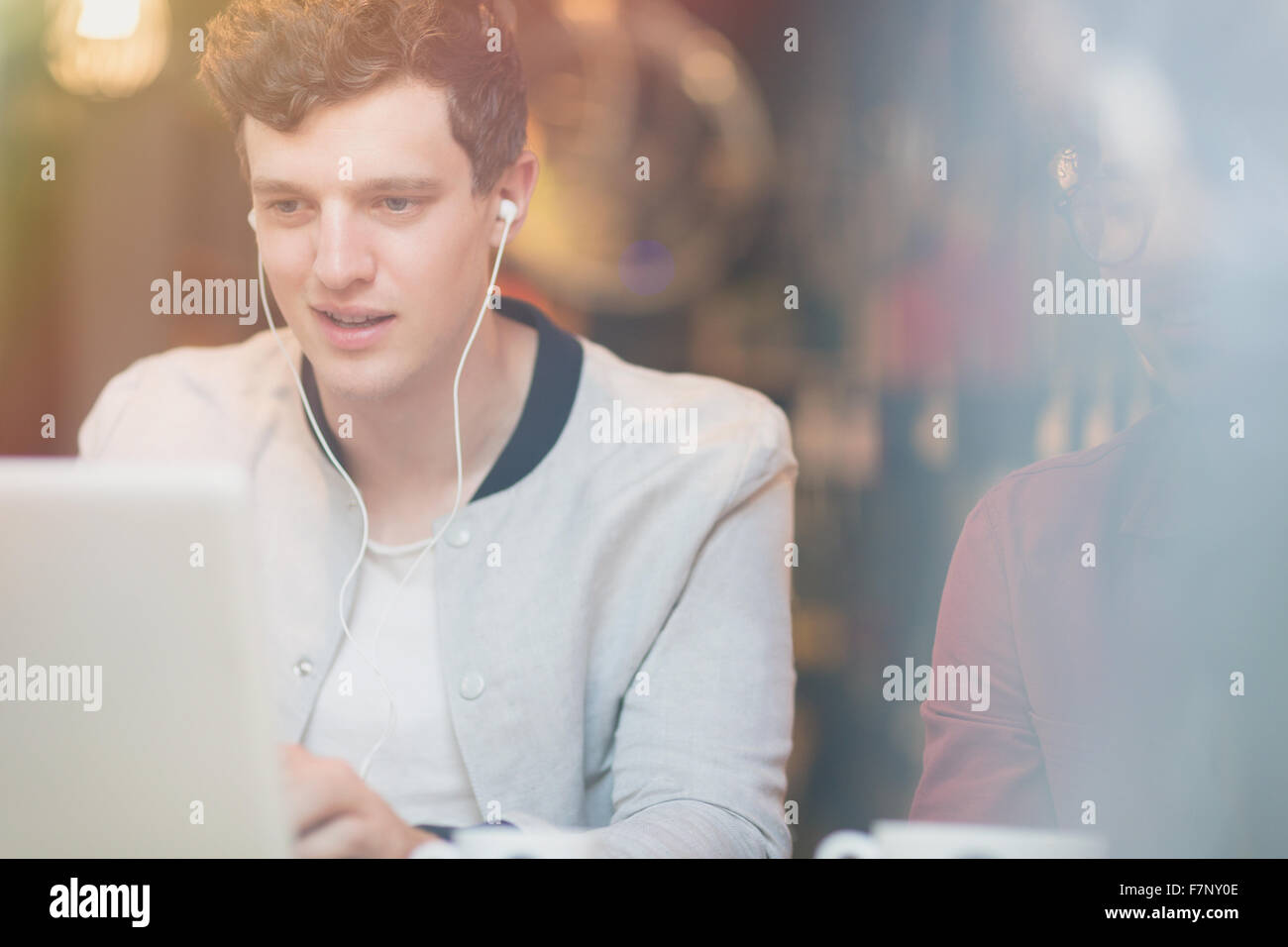 Man listening to music on headphones and using laptop Stock Photo