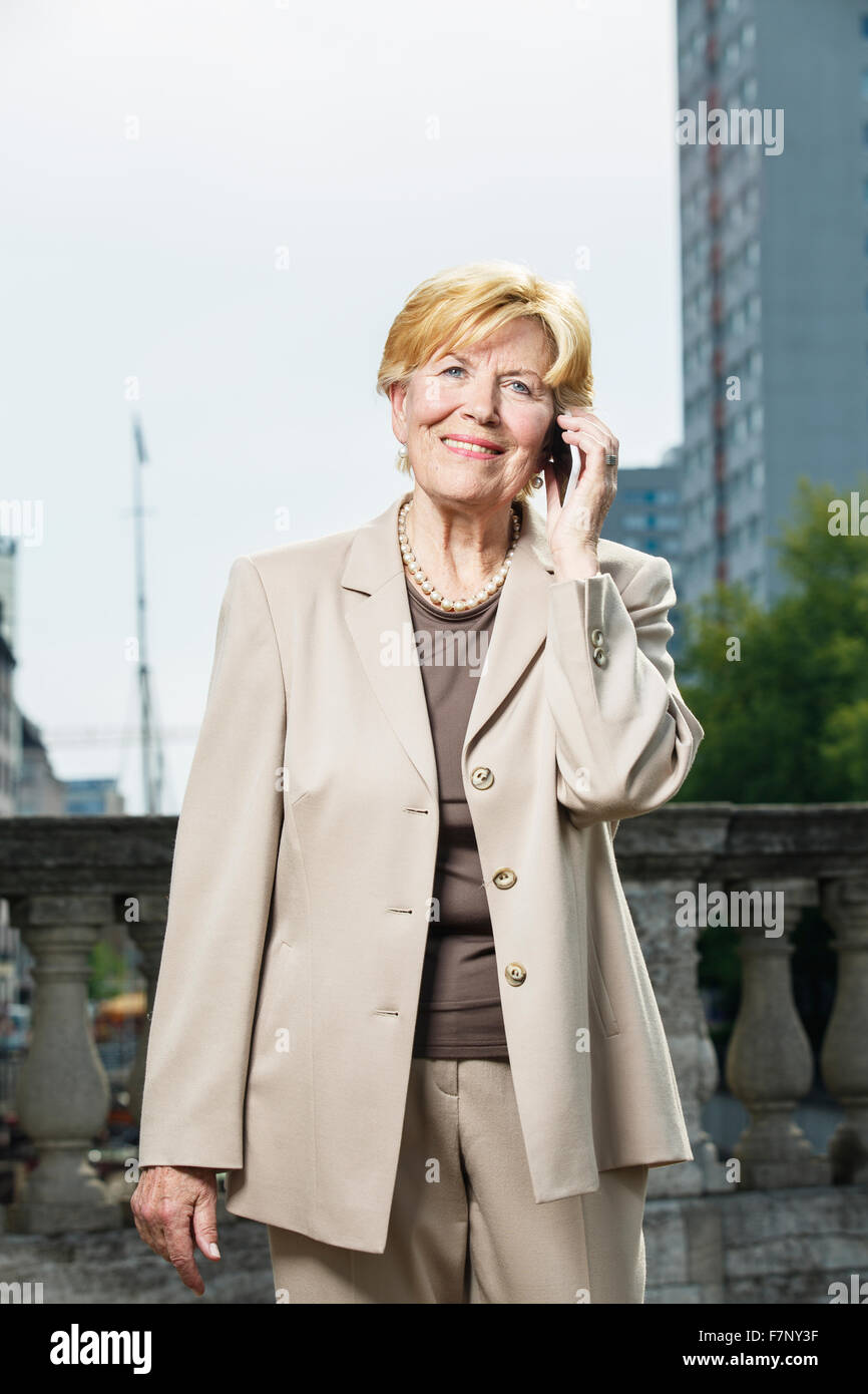 Germany, Berlin, portrait of smiling senior businesswoman telephoning with smartphone Stock Photo