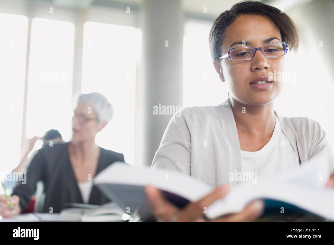 Serious woman reading book in adult education classroom Stock Photo