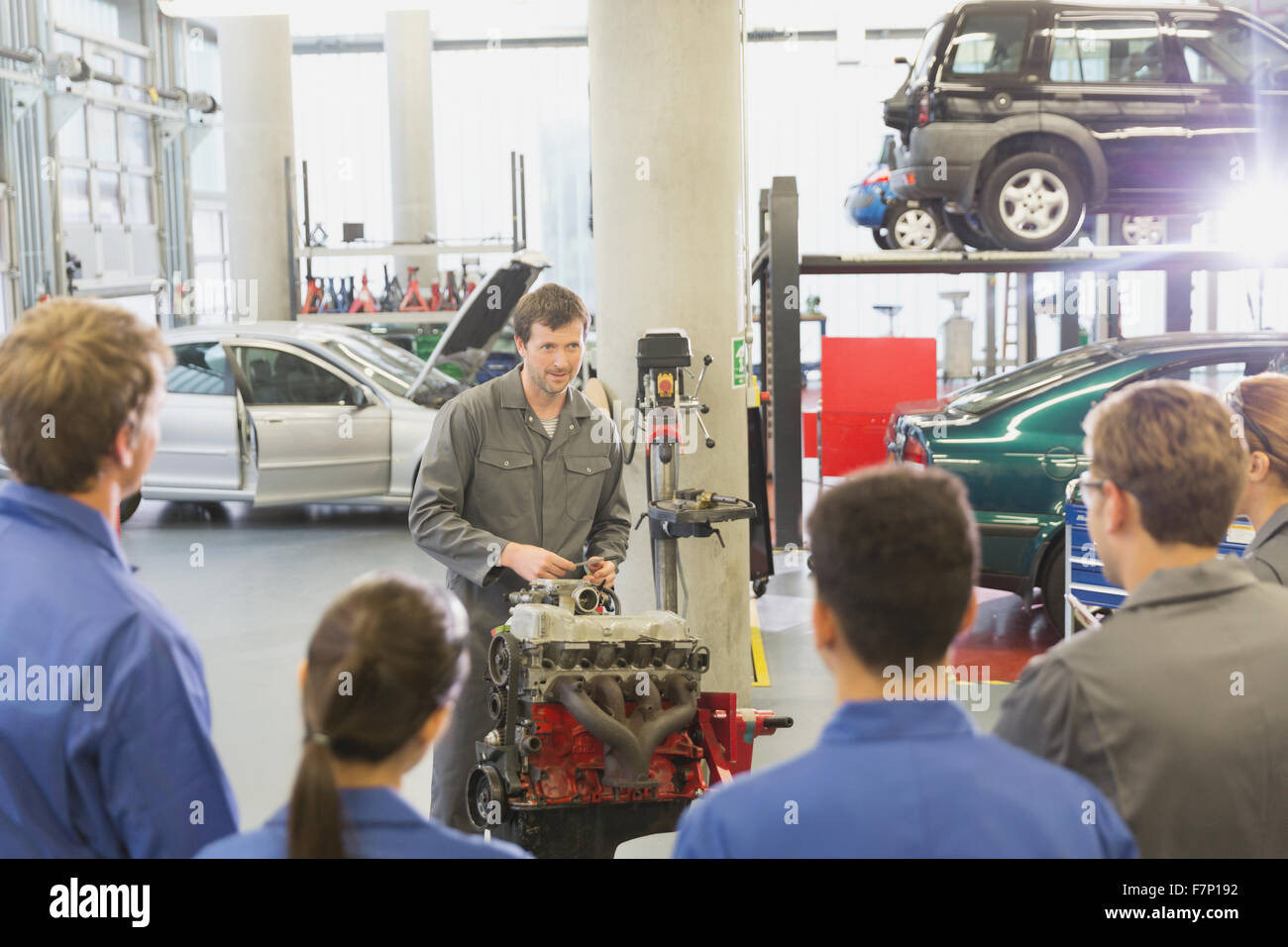 Mechanic explaining car engine to students in auto repair shop Stock Photo