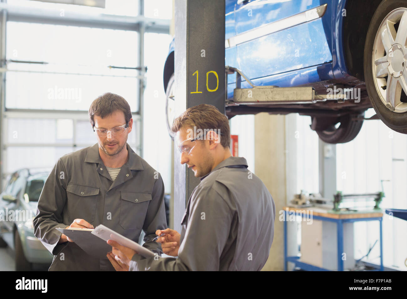 Mechanics reviewing paperwork in auto repair shop Stock Photo