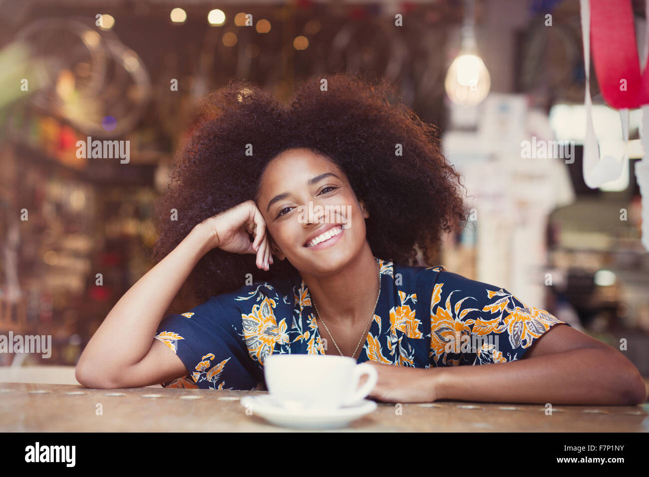 Portrait smiling woman with afro drinking coffee in cafe Stock Photo