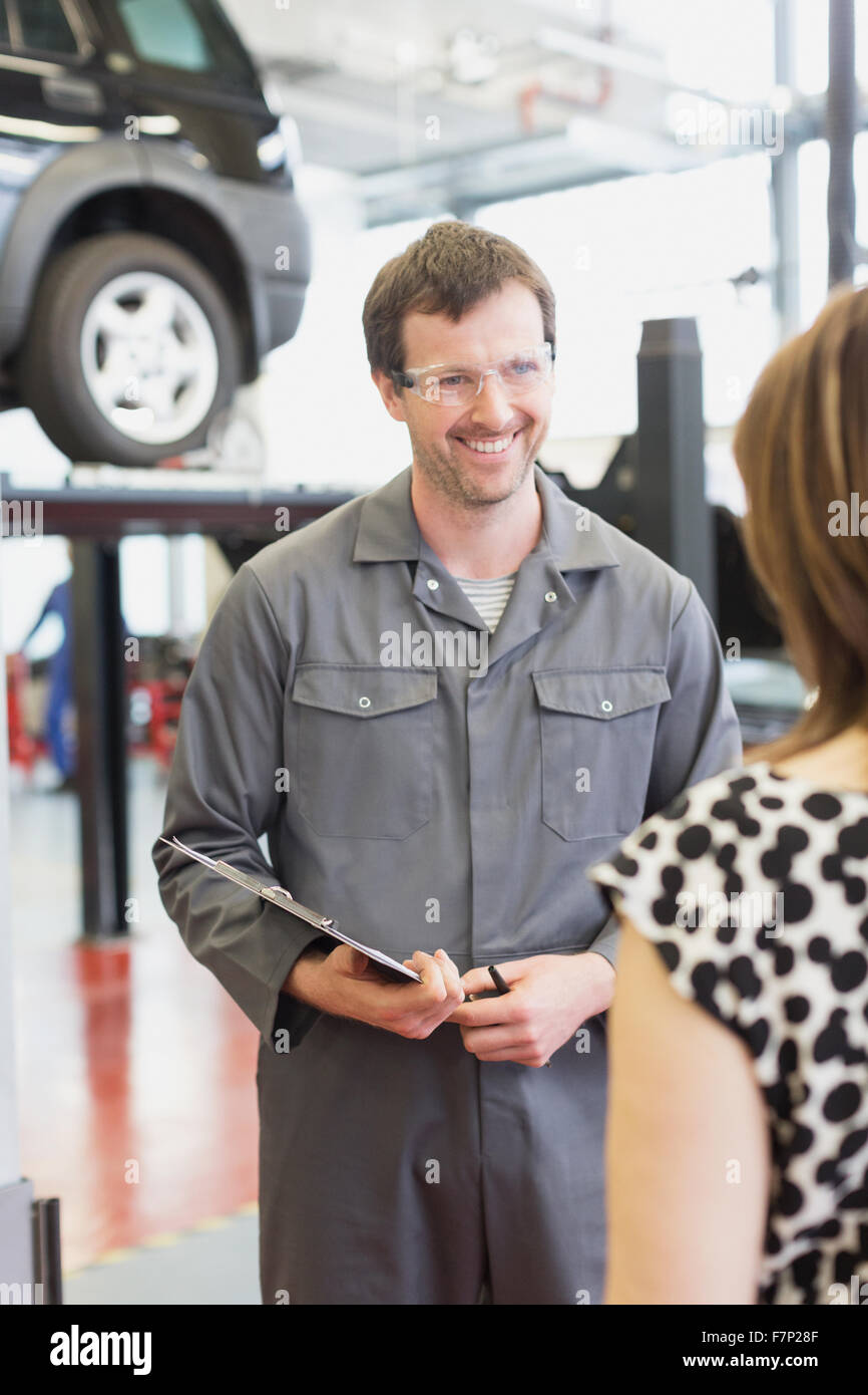 Mechanic with clipboard talking to customer in auto repair shop Stock Photo