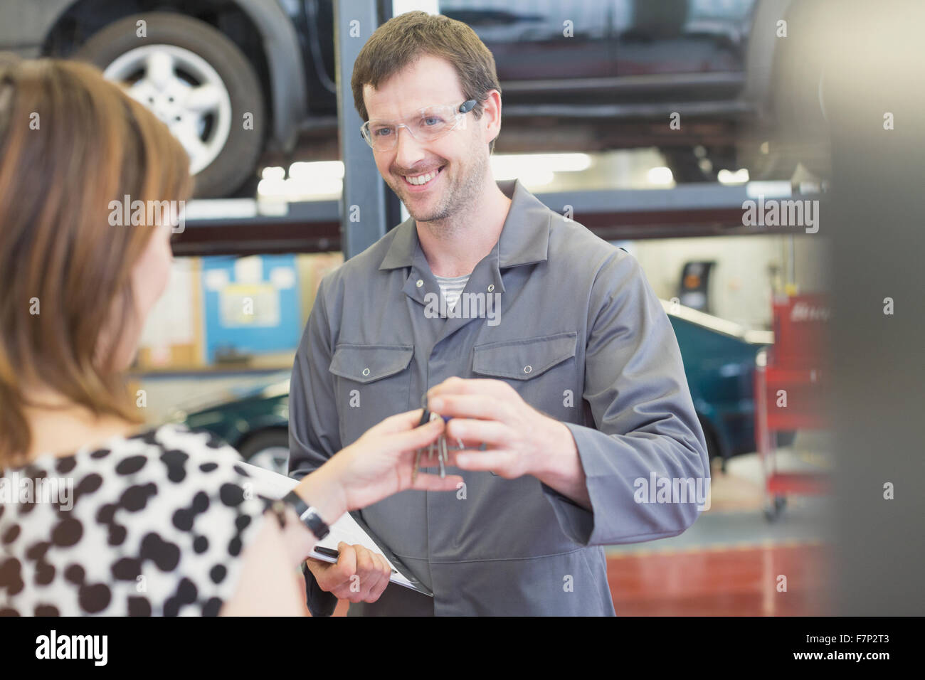Mechanic taking keys from woman in auto repair shop Stock Photo