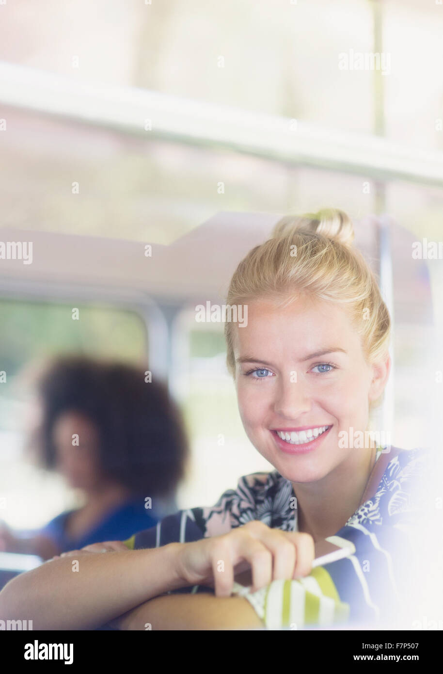 Portrait smiling blonde woman holding cell phone on bus Stock Photo