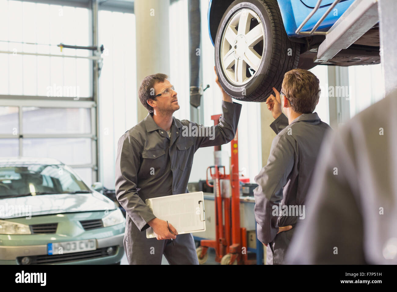 Mechanics examining and discussing tire in auto repair shop Stock Photo