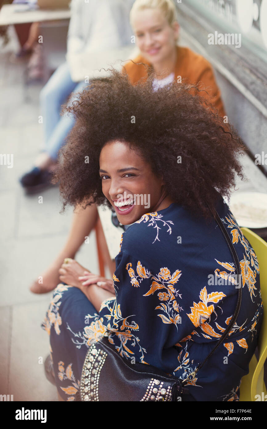 Portrait enthusiastic woman with afro at sidewalk cafe Stock Photo