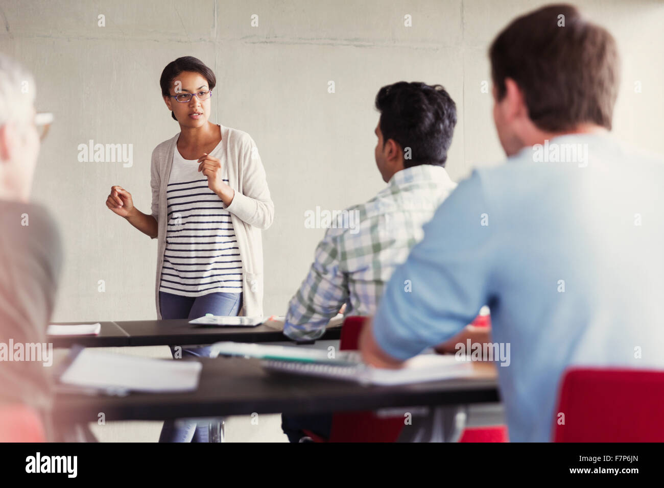 Teacher speaking to students in adult education classroom Stock Photo