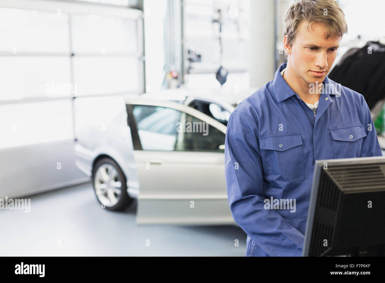 Mechanic working at computer in auto repair shop Stock Photo