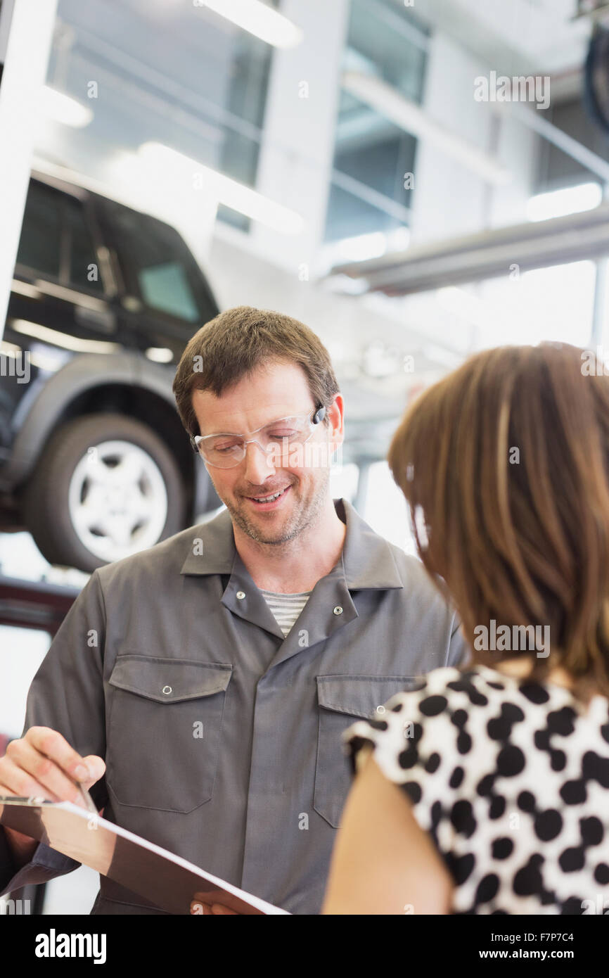 Mechanic with clipboard talking to customer in auto repair shop Stock Photo