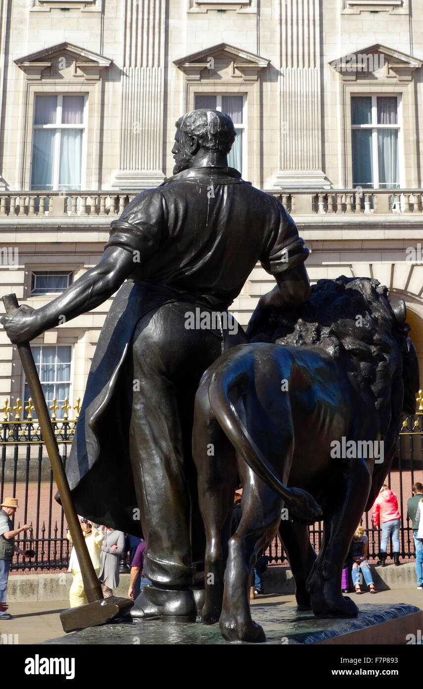figure representing Manufacture (a blacksmith in modern costume with a hammer and a scroll) with lion. This figure appears on the base of the Victoria Memorial, at the end of The Mall in London Stock Photo