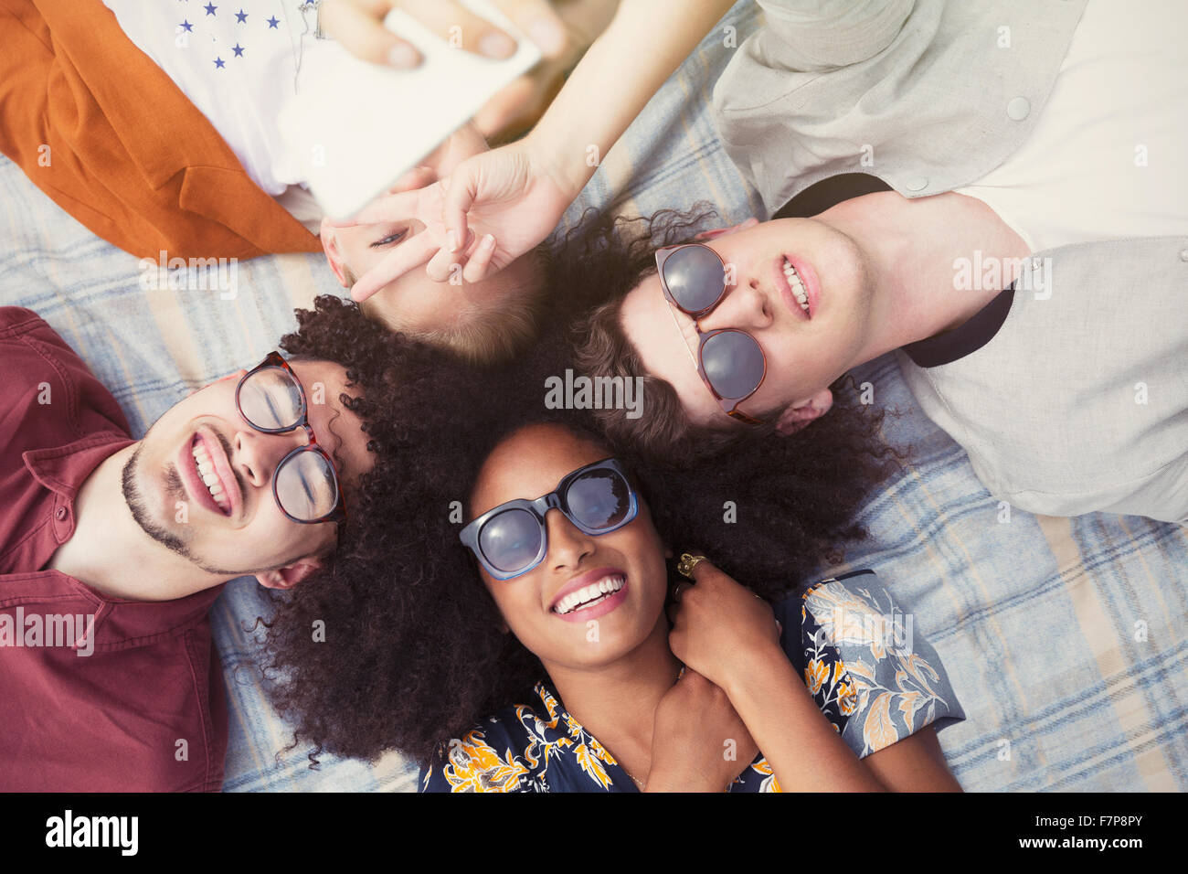 Overhead portrait smiling friends laying in circle on blanket Stock Photo