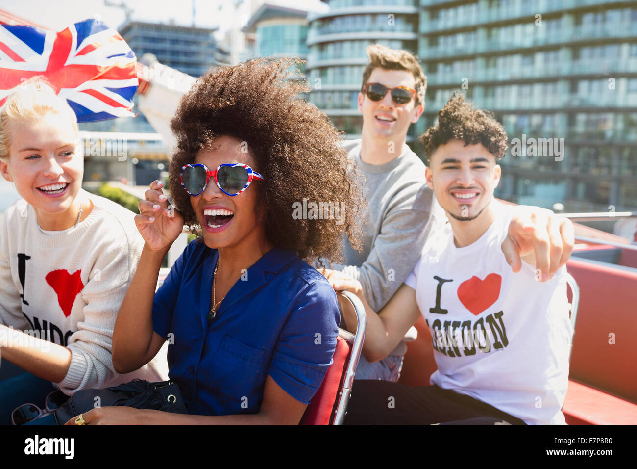 Portrait enthusiastic friends with British flag riding double-decker bus Stock Photo