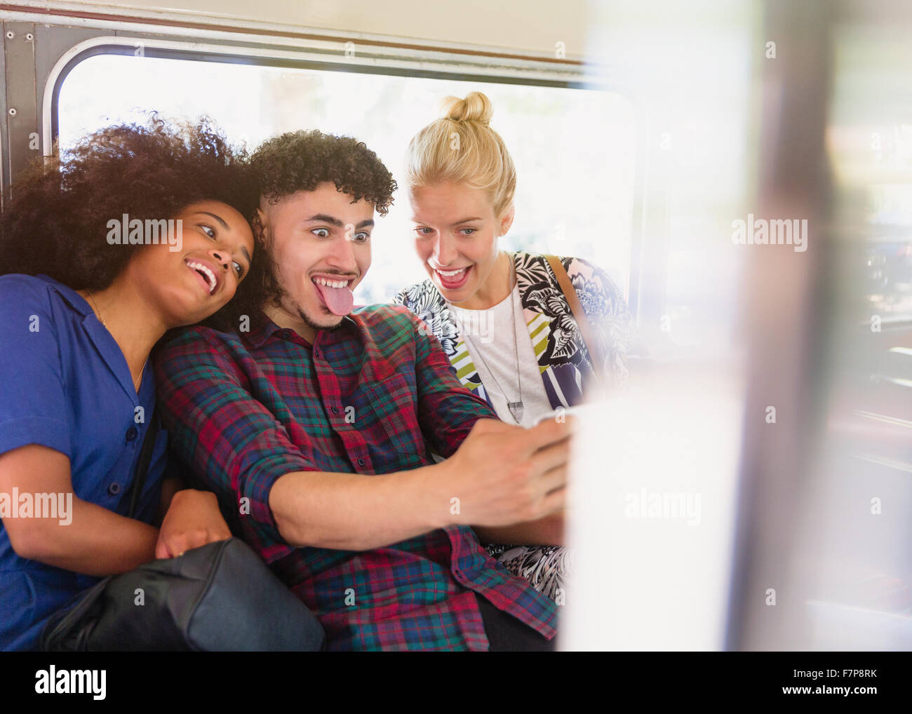 Playful friends taking selfie making faces on bus Stock Photo