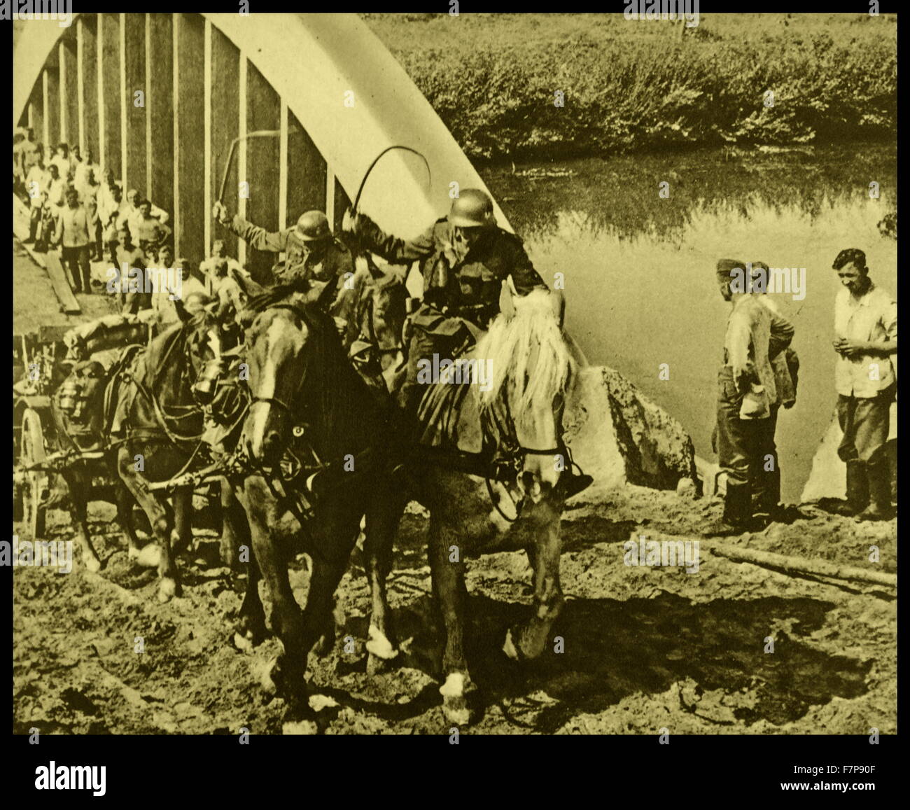 German forces advancing through Poland, towards Warsaw. German troops are shown crossing a bridge with horse and carriage, while Polish prisoners of war closely follow. Dated 1939. Stock Photo