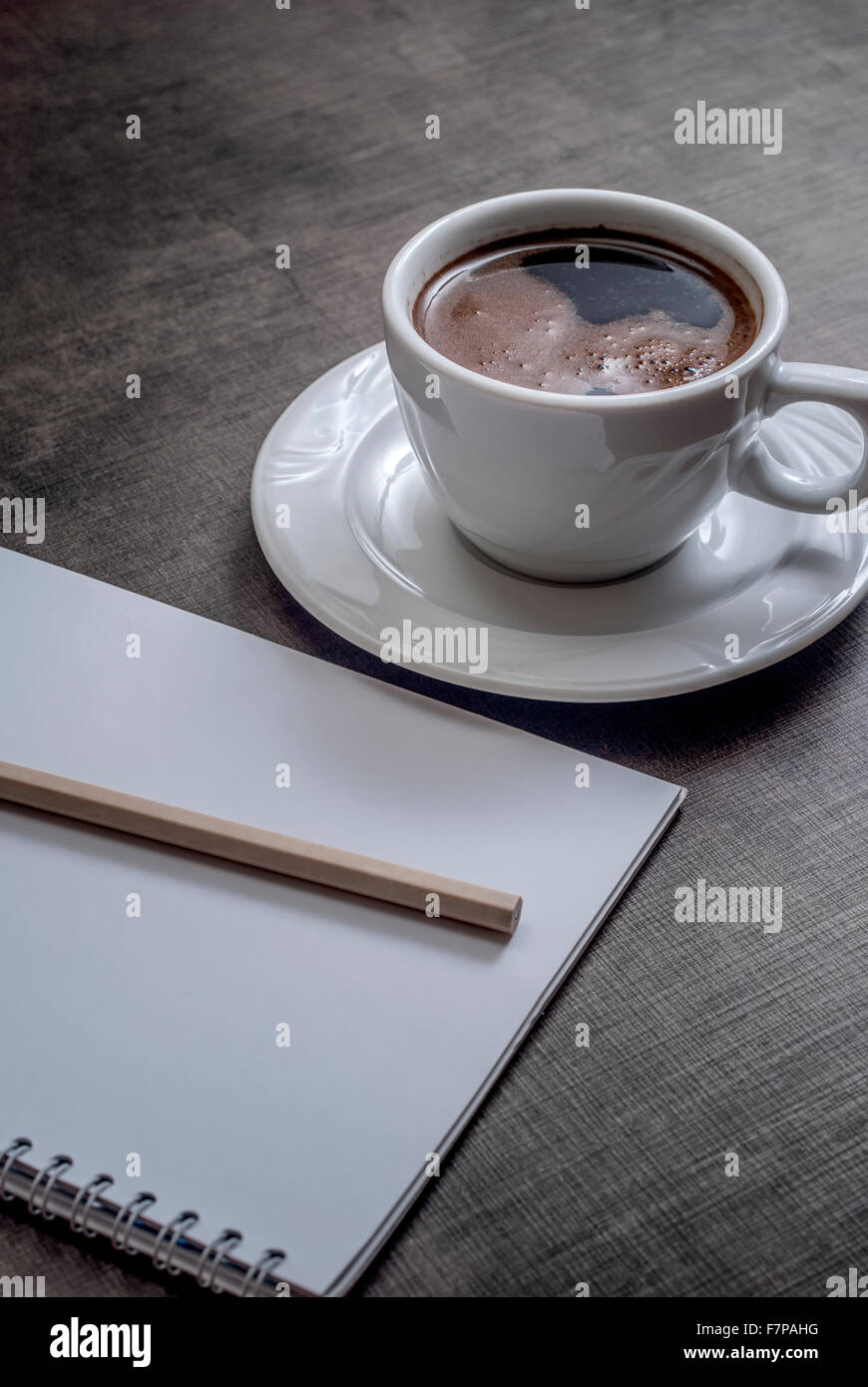 A blank white notebook and cup of coffee on the wooden table Stock Photo