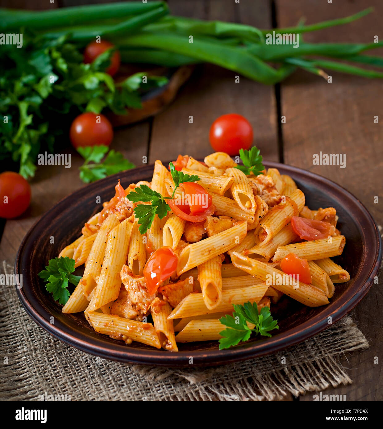 Penne pasta in tomato sauce with chicken, tomatoes decorated with