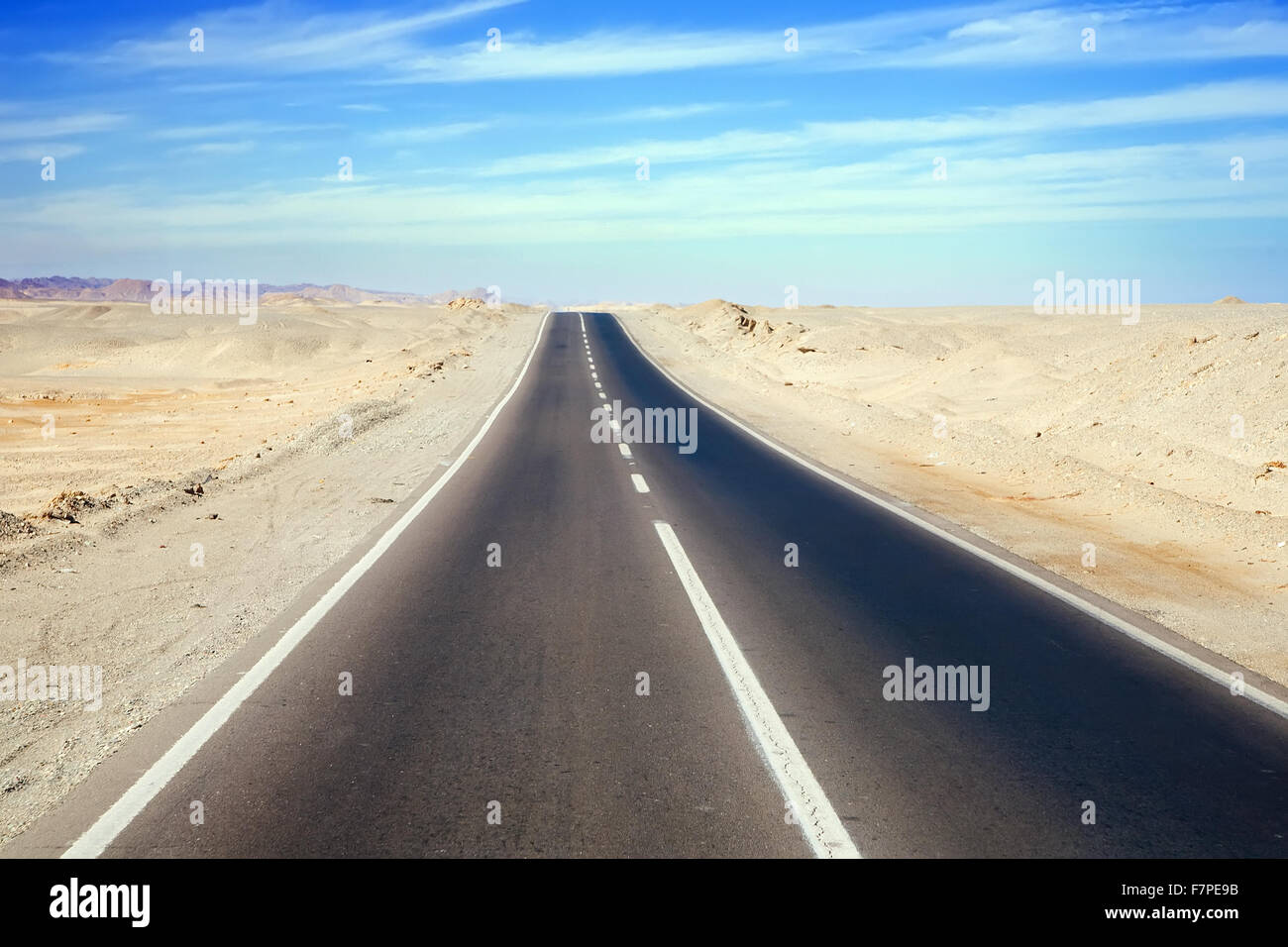 Road through desert landscape under cloudy sky Stock Photo - Alamy