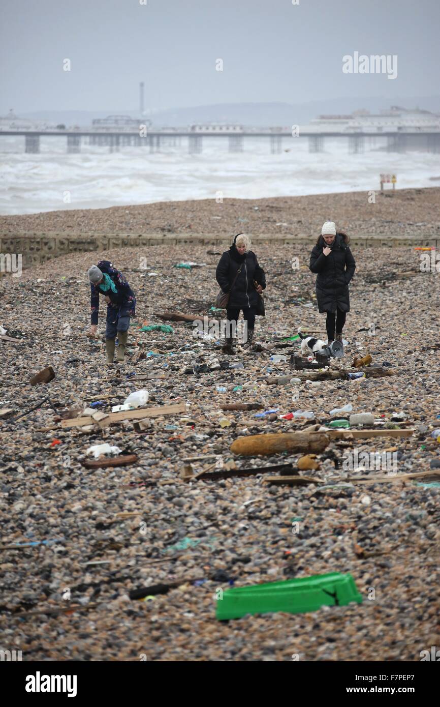 Three women walk amongst litter washed ashore on Brighton Beach 2 December 2015 after high winds and seas continue to batter the Stock Photo