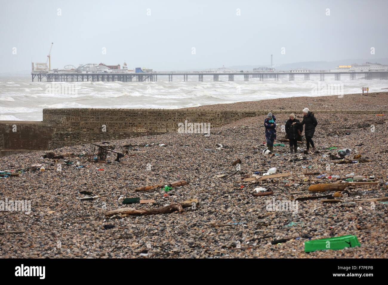 Three women walk amongst litter washed ashore on Brighton Beach 2 December 2015 after high winds and seas continue to batter the Stock Photo