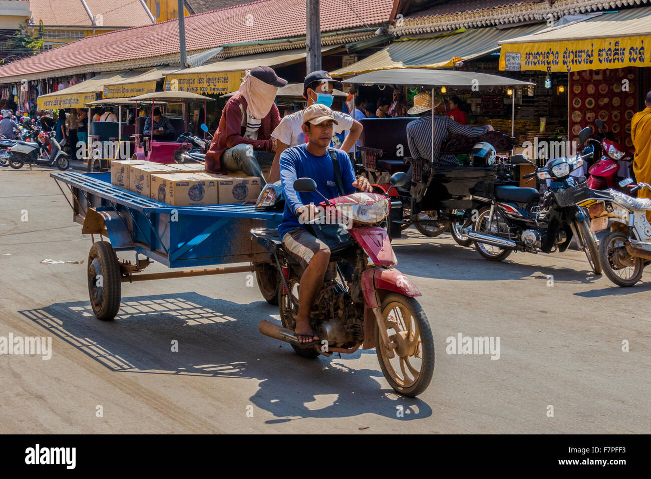 Motorcycle towing cart with goods on from one area to the other in Siem Reap Cambodia Stock Photo