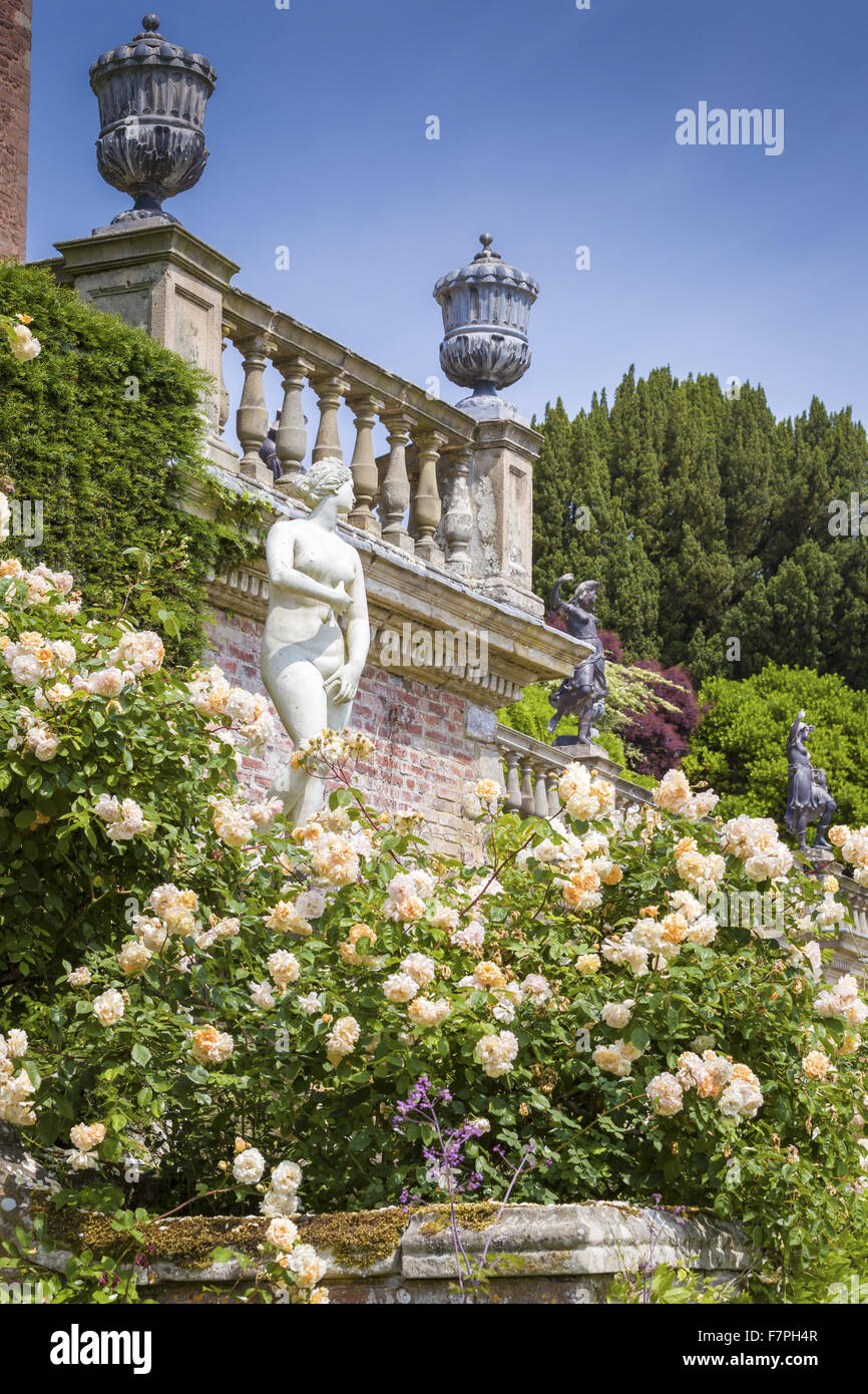 Tumbling Roses A classical statue, surrounded by tumbling roses, clematis and ferns on ...