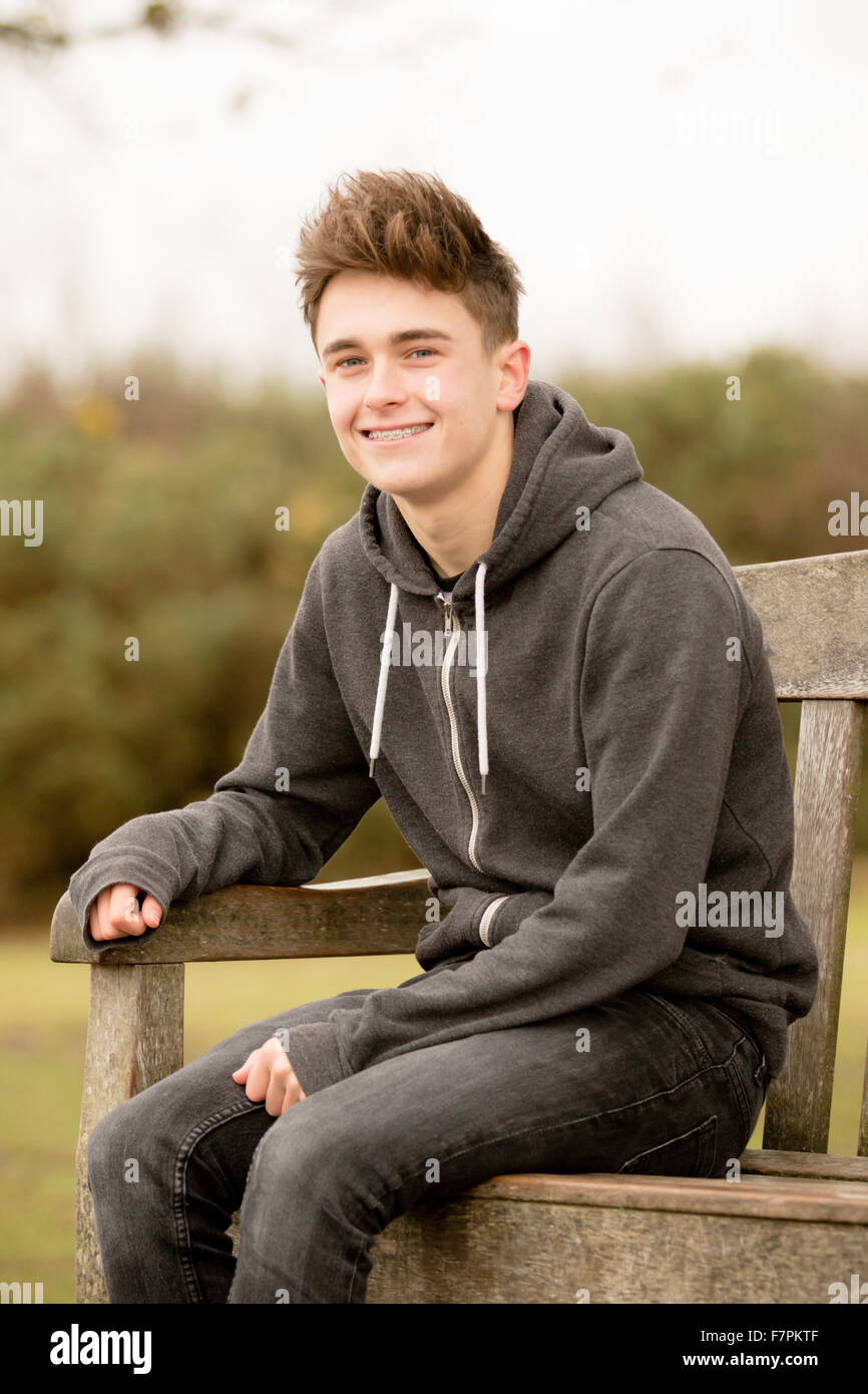 Teenage boy sitting on a park bench Stock Photo - Alamy