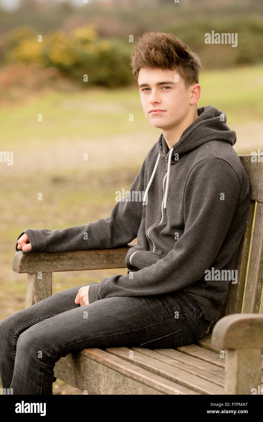 Teenage boy sitting on a park bench Stock Photo - Alamy
