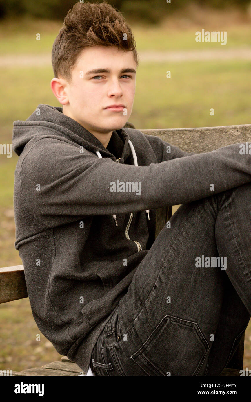 Teenage boy sitting on a park bench Stock Photo - Alamy