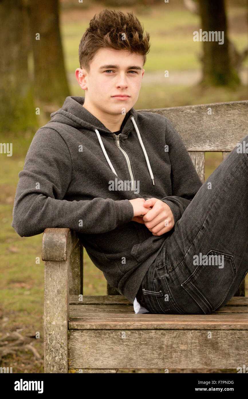 Teenage boy sitting on a park bench Stock Photo - Alamy