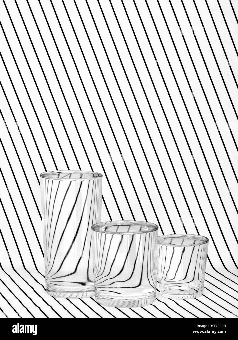 Three full glasses on striped fabric, black and white. Refraction. Stock Photo