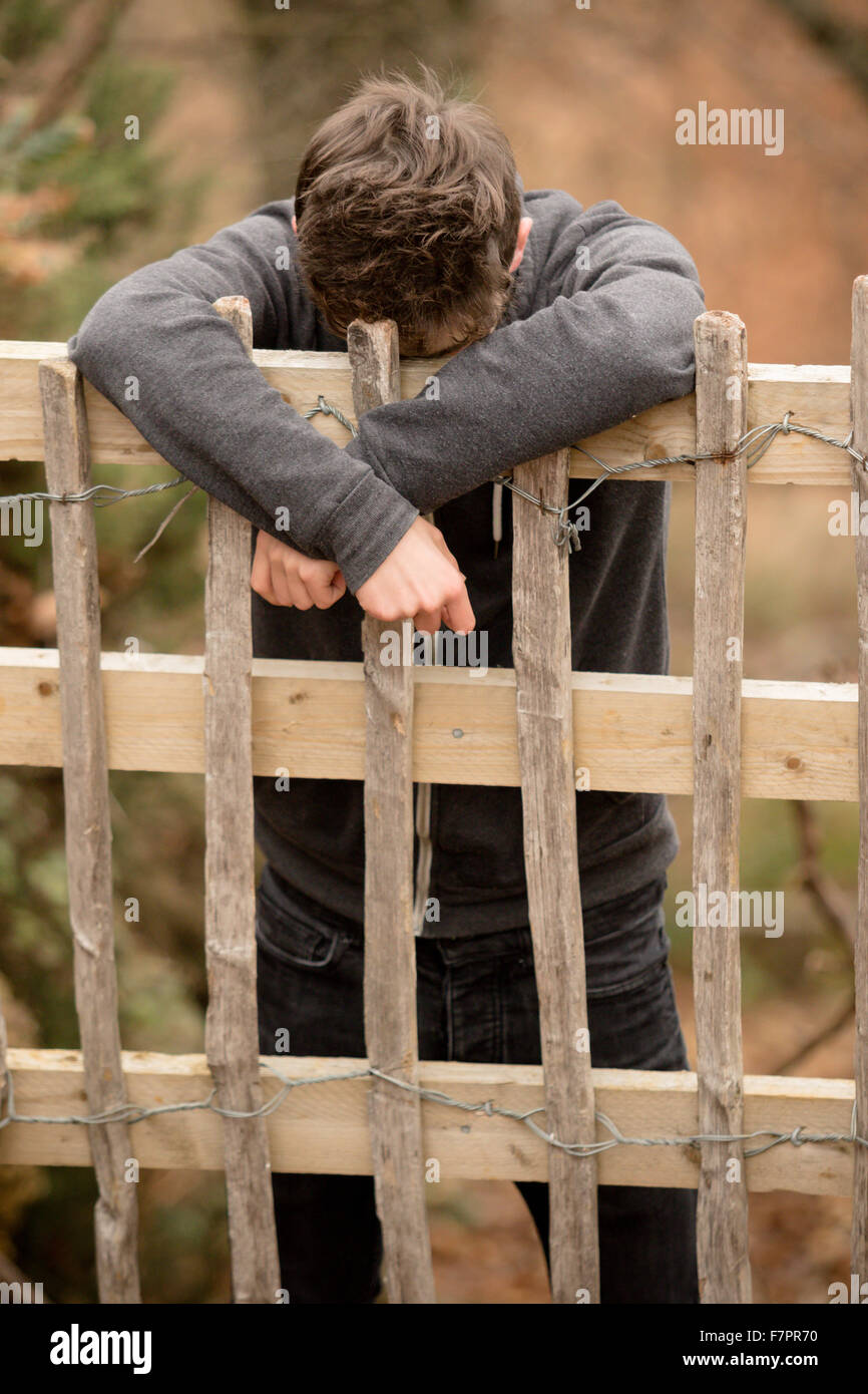 Sad Teenage Boy Leaning On A Fence Stock Photo