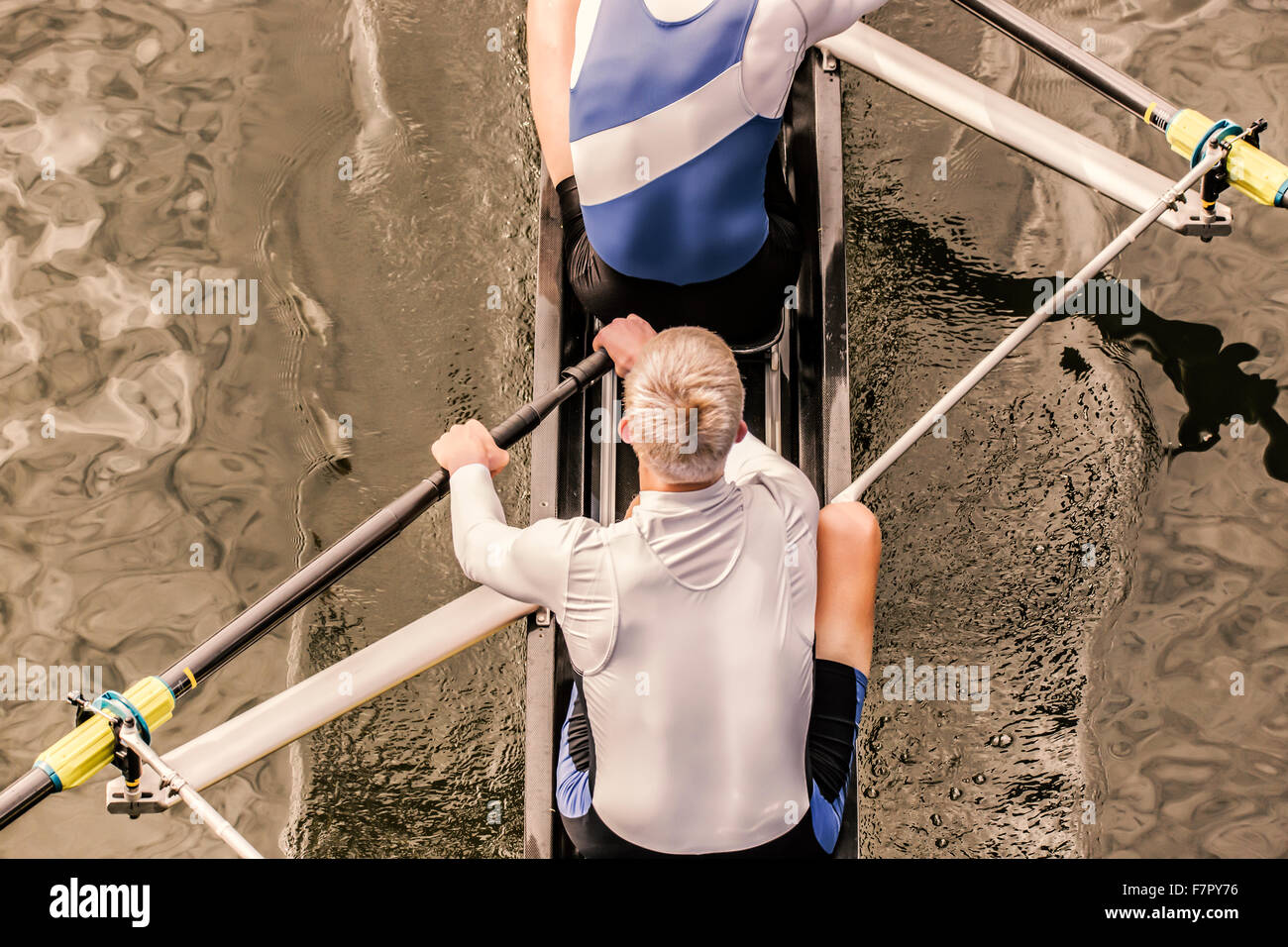 Top view of two athletic competition rower, who stroke their paddle through the water. Stock Photo