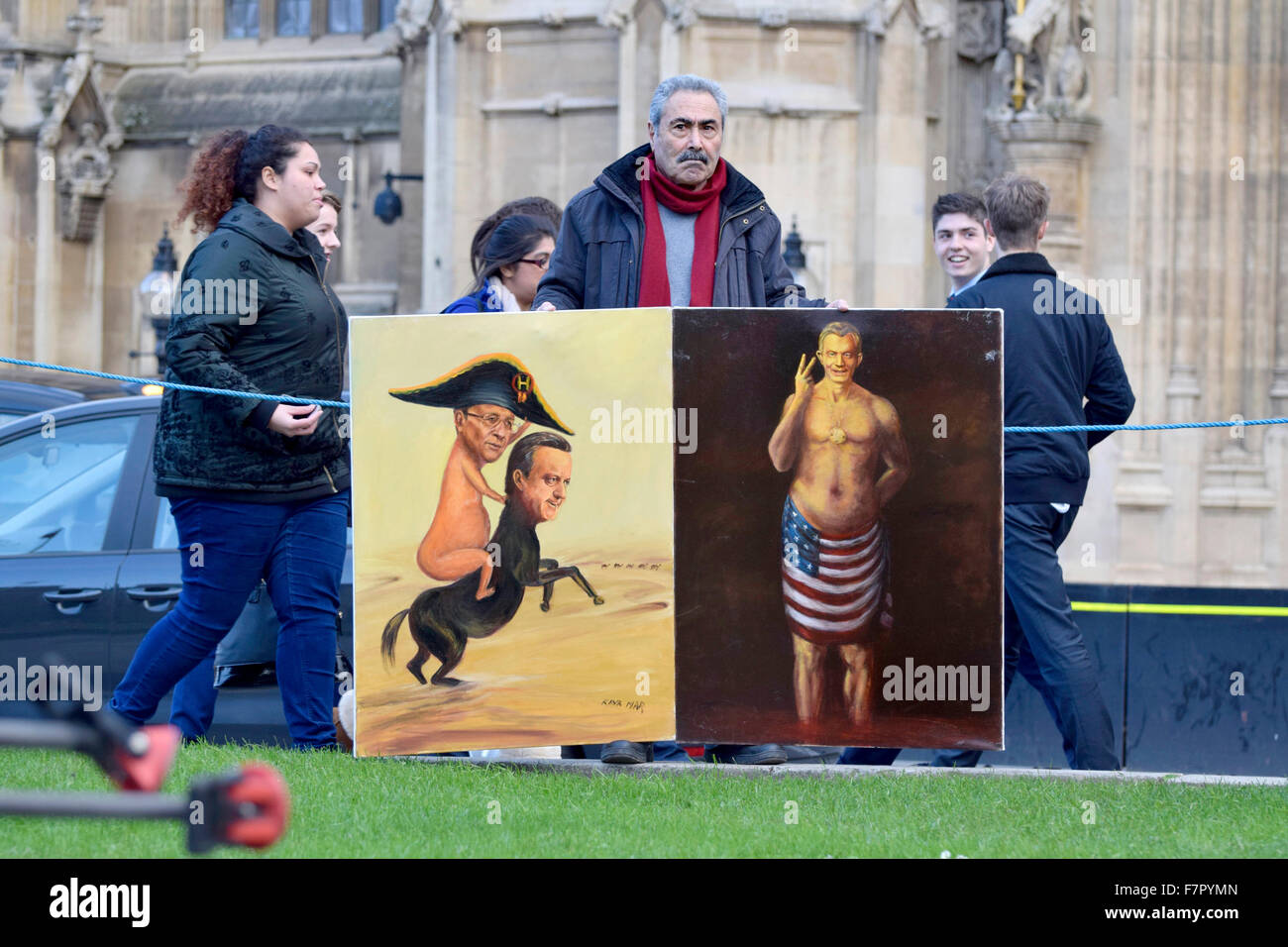 London, UK. 2nd December, 2015. The world's media and a small number of protesters gather on College Green opposite the Houses of Parliament as MPs debate the bombing of ISIS in Syria. Satirical artist Kaya Mar with two of his 'warmonger' paintings Credit:  PjrNews/Alamy Live News Stock Photo