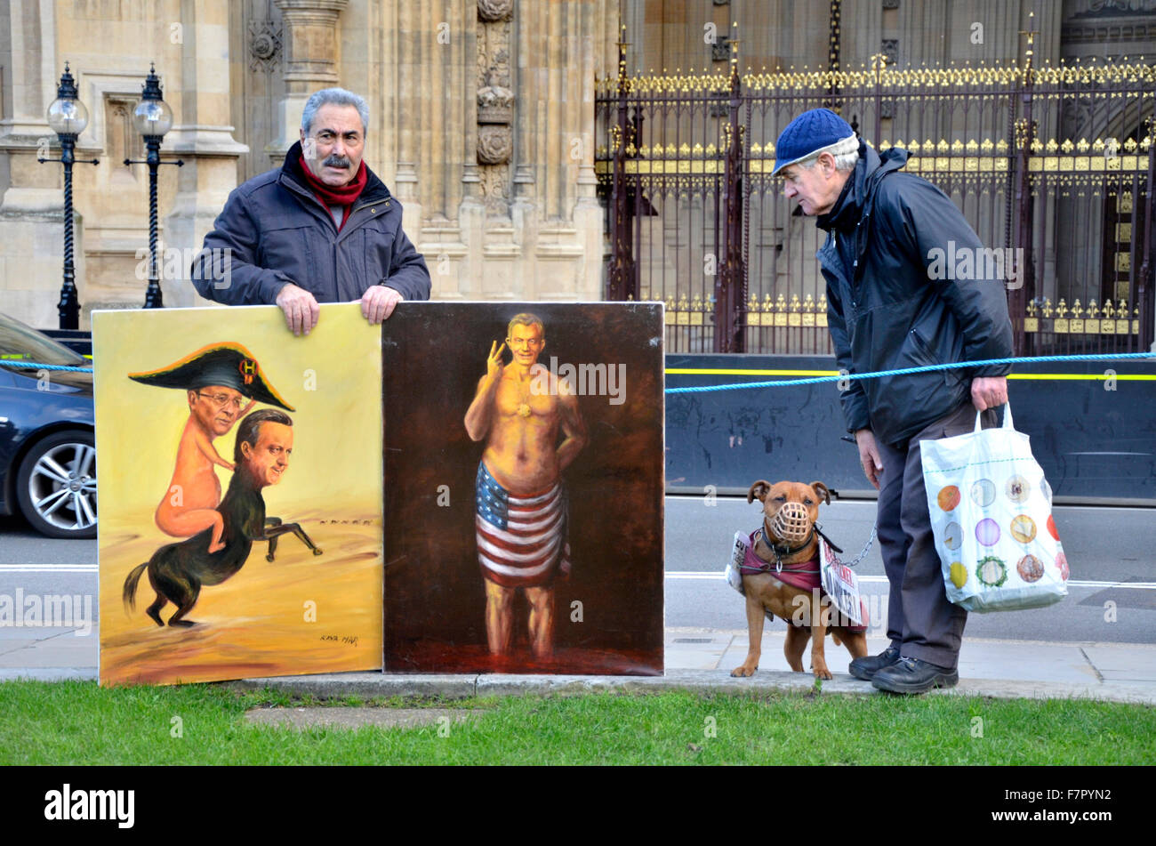 London, UK. 2nd December, 2015. The world's media and a small number of protesters gather on College Green opposite the Houses of Parliament as MPs debate the bombing of ISIS in Syria. Satirical artist Kaya Mar shows two of his 'warmonger' paintings to veteran campaigner Stuart Holmes Credit:  PjrNews/Alamy Live News Stock Photo