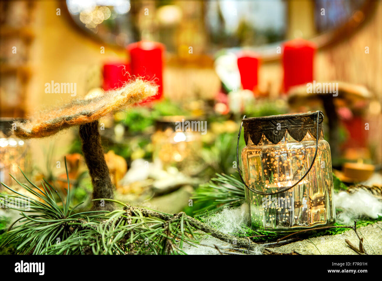 Close look to an advent wreath with handmade felt mushroom and candle illuminated glass potty in the foreground Stock Photo