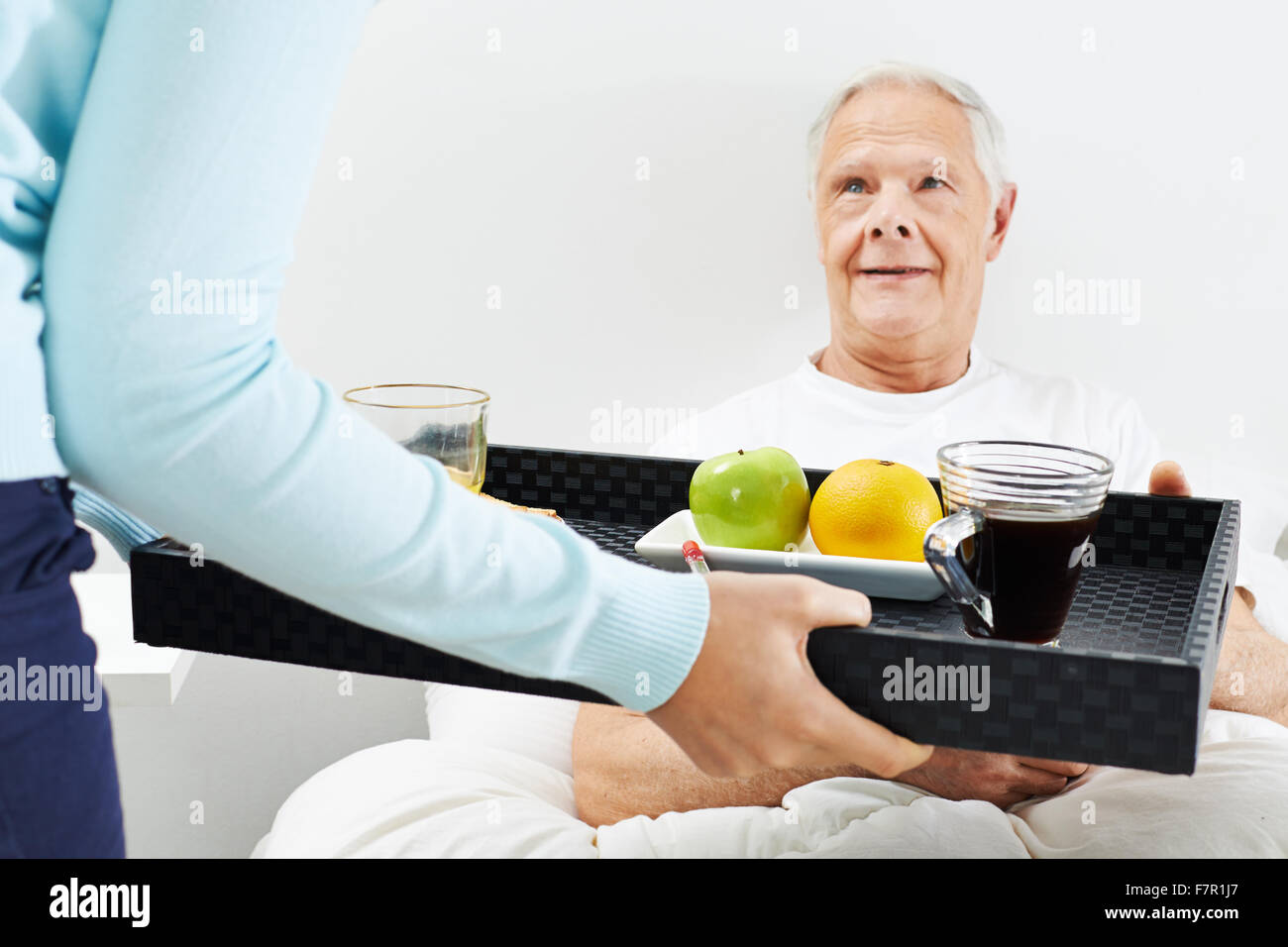 Old man eating breakfast in bed at home Stock Photo