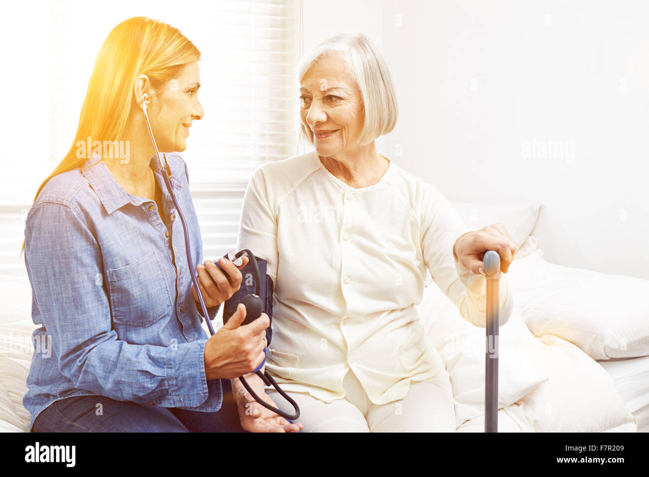 Woman doing blood pressure monitoring in nursing home for senior woman
