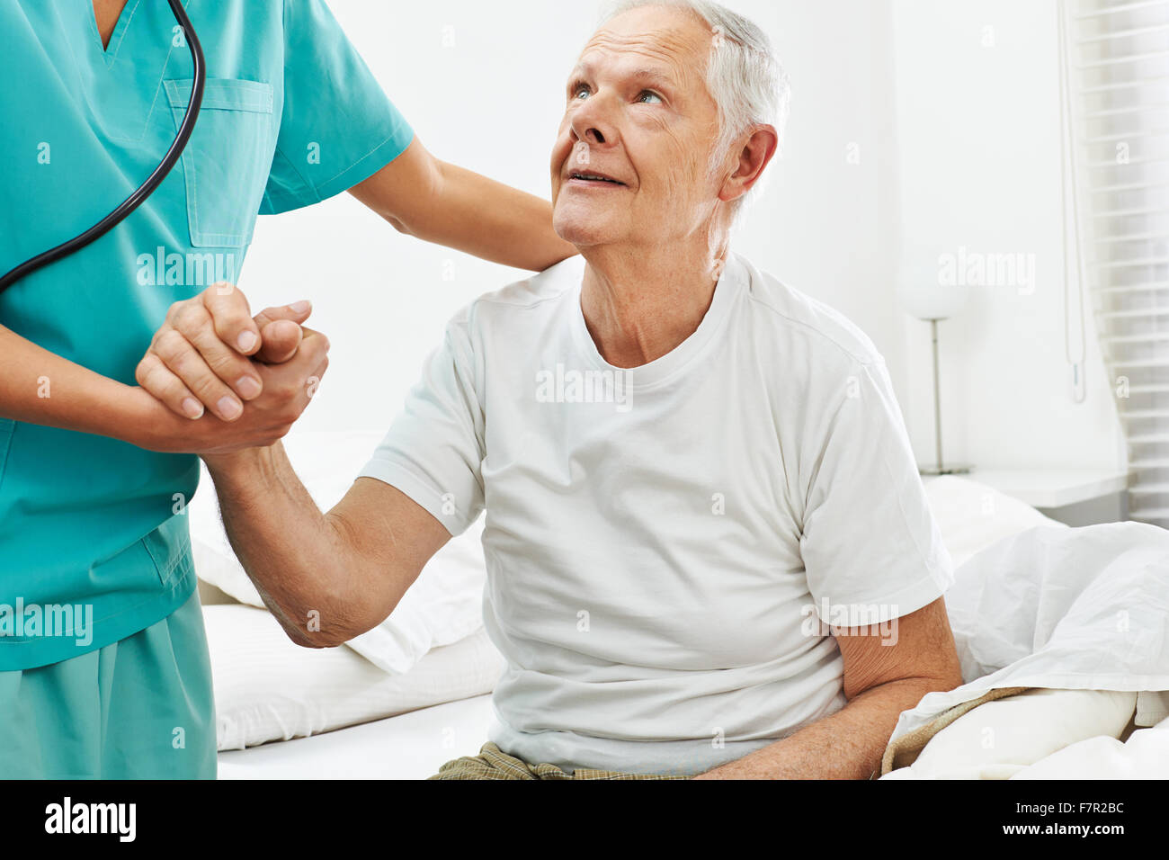 Geriatric caregiver helping old man getting up from bed Stock Photo Alamy