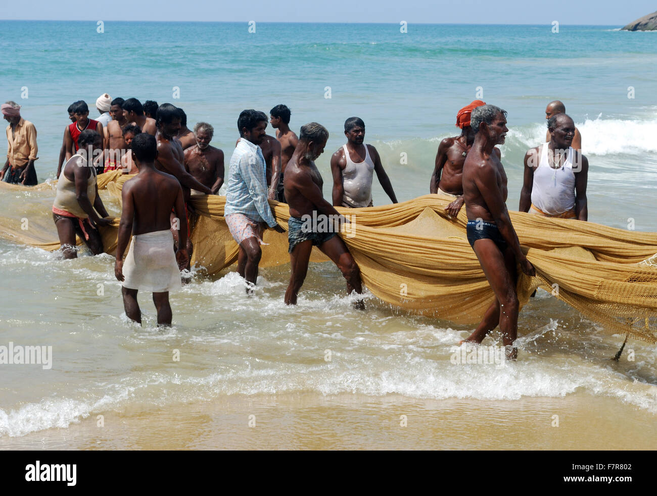 fishermen pulling the fishing nets at kovalam beach kerala india Stock