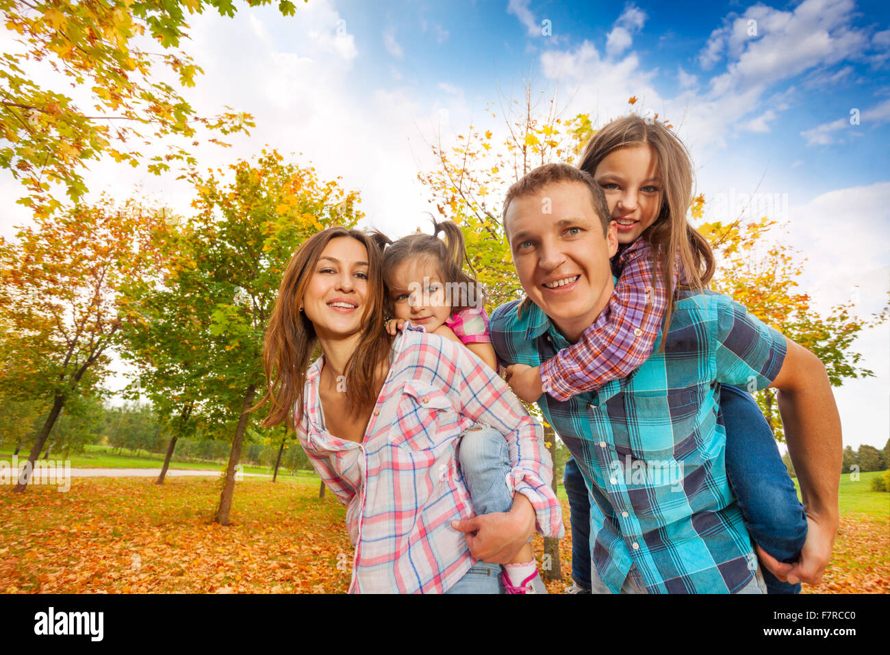 Happy family carry little girls in the autumn park Stock Photo