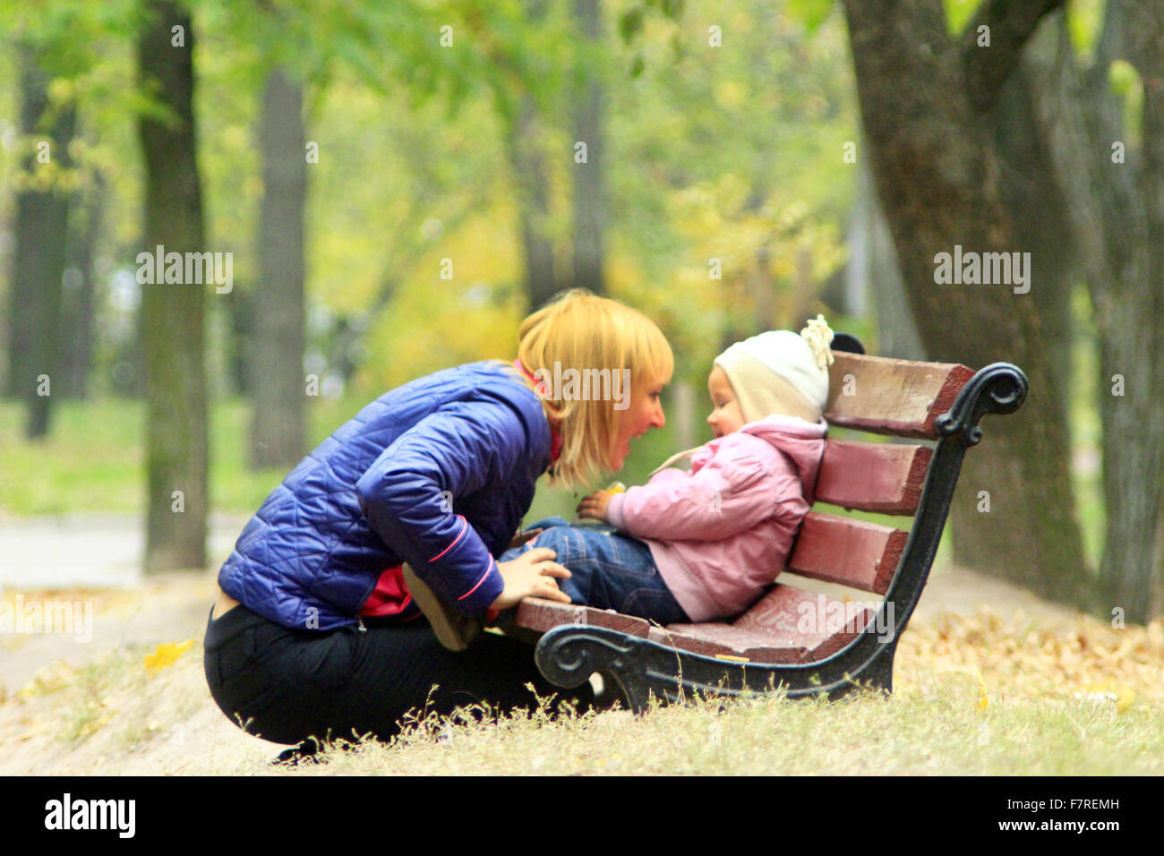 Mother plays with her daughter sitting on the bench in the park Stock ...