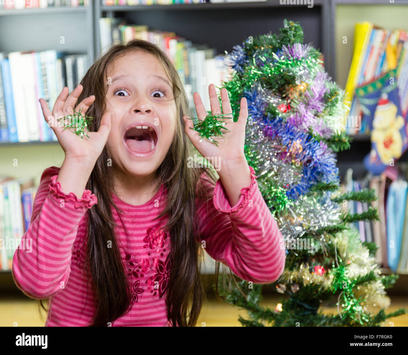 Young girl decorating Christmas tree making funny face Stock Photo