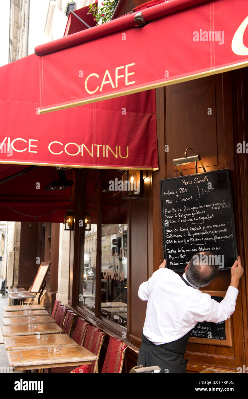 A waiter hanging the day's menu out a cafe in the Marais district of Paris, France Stock Photo