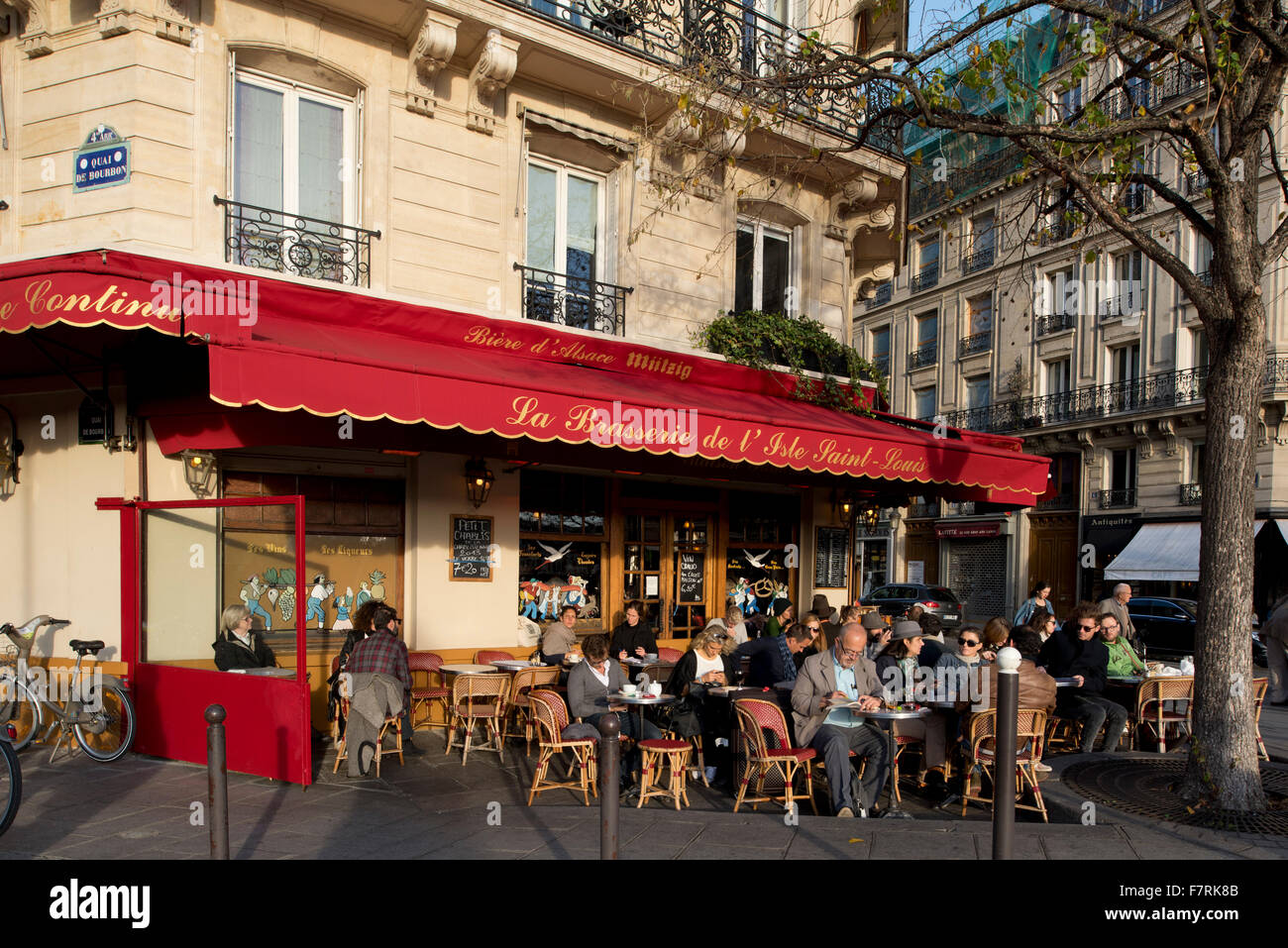 People sitting at pavement tables at a busy cafe on the Ile St Louis; Paris, France Stock Photo